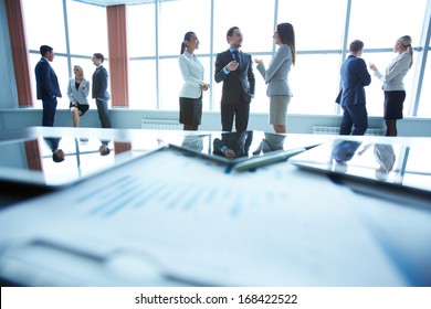 Business People Interacting In Office With Workplace In Front Of Them