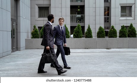 Business people leaving office building, new employee trying to make friends