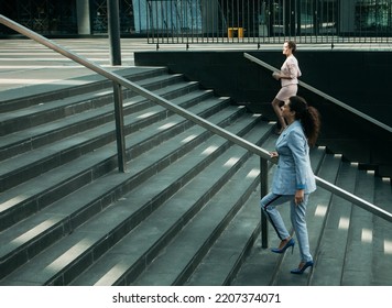 Business, People And Lifestyle Concept: Two Young Business Women While Walking Up Stairs Near Modern Office Building.