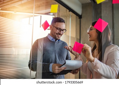 Business People Looking At Post It Notes On Notice Board. Brainstorming, Discussion, Showing, Explaining, Teamwork. Young Woman At Work Showing Ideas To Colleague