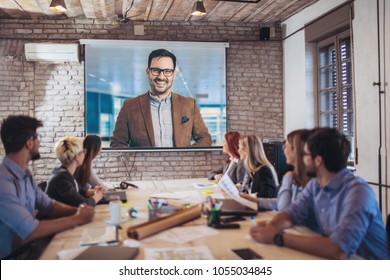 Business people looking at projector during video conference in office