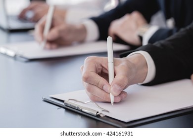 Business people making notes sitting in a row at conference - Shutterstock ID 424161931