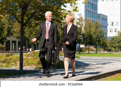 Business People - Mature Or Senior -  Talking Outdoors And Walking In A Park