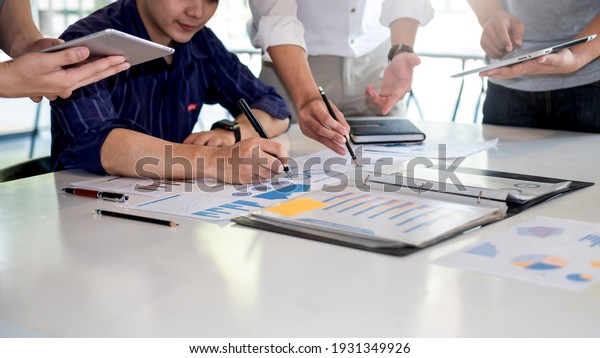 Business people meeting to find analytical\
ideas pointing to the graph at the\
office.