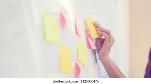 Business people meeting at office and use post it notes to share idea. Brainstorming concept. Sticky note on glass wall.business women working and communicating together in creative office - Shutterstock ID 1125000476