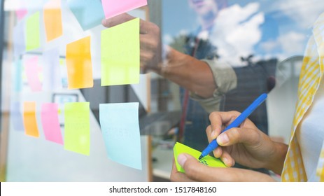 Деловые люди встречаются в офисе и используют липкие заметки на стеклянной стене в офисе, различные сотрудники, люди, планирующие группы, совместная работа, стратегия мозгового штурма