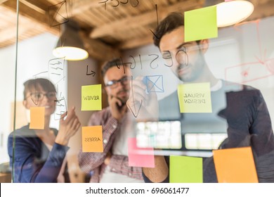 Business people meeting at office and use post it notes to share idea. Brainstorming concept. Sticky note on glass wall. - Shutterstock ID 696061477