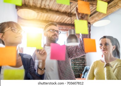 Business people meeting at office and use post it notes to share idea. Brainstorming concept. Sticky note on glass wall. - Shutterstock ID 703607812