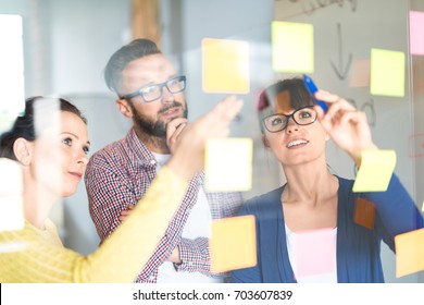 Business people meeting at office and use post it notes to share idea. Brainstorming concept. Sticky note on glass wall. - Shutterstock ID 703607839