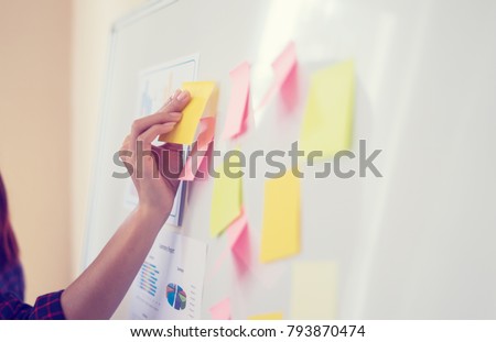 Business people meeting at office and use post it notes to share idea. Brainstorming concept. Sticky note on glass wall.business women working and communicating together in creative office