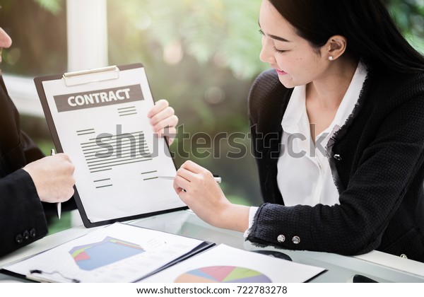 Business people meeting signing agreement sitting\
at desk team work group on conference discussing financial diagram\
graph business charts