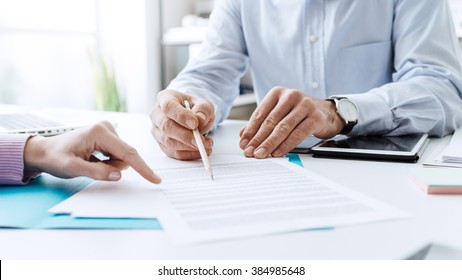 Business people negotiating a contract, they are pointing on a document and discussing together - Shutterstock ID 384985648