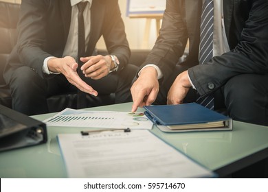 Business people negotiating a contract, they are pointing on a document and discussing together. Two businessmen are negotiating in office.