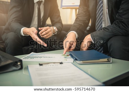 Business people negotiating a contract, they are pointing on a document and discussing together. Two businessmen are negotiating in office.