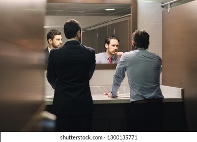 Business People In Office Bathroom. Young Man Using Corporate Restroom, Washroom And Lavatory. Public Toilet In Building With Manager Brushing Teeth After Lunch Break