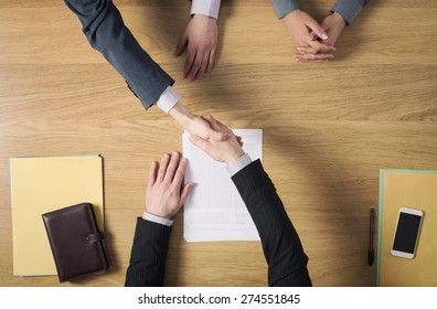 Business People At Office Desk Handshaking After Signing An Agreement, Hands Top View, Unrecognizable People