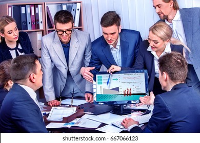 Business People Office Life Of Team People Working With Papers Sitting Table . Schemas And Diagrams On Computer Monitor. Team Works Together Project. Woman Takes Initiative.