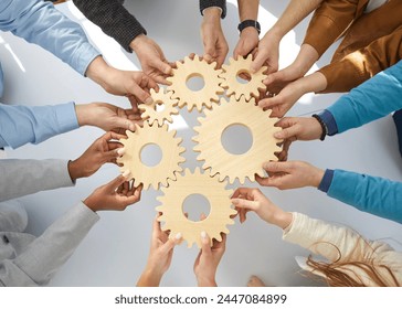 Business people or office workers hold wooden gears that symbolize well-coordinated teamwork. Top view close up of hands of multiracial men and women standing in circle. Concept business cooperation - Powered by Shutterstock