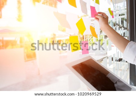 business people post it notes to share idea discussing and planning in glass wall at meeting room, teamwork concept