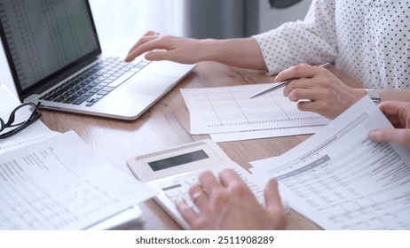 Business people professionals analyzing financial documents. Two colleagues working together, reviewing papers and using a laptop. Finance audit and taxes - Powered by Shutterstock