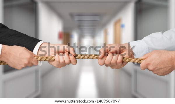 Business people pulling rope in opposite\
directions at office
