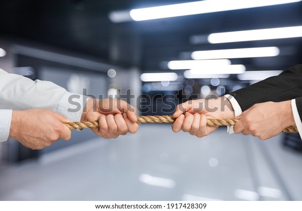 Business people pulling rope in opposite\
directions at office