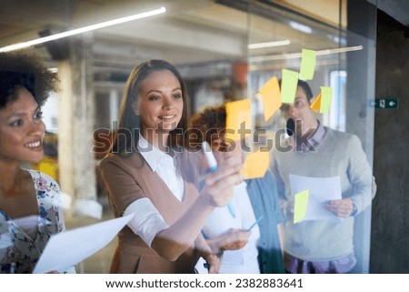 Business people putting sticky notes on a glass board in a modern office
