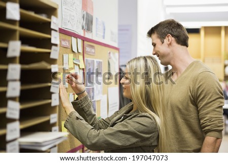Business people reading reminders on bulletin board in office