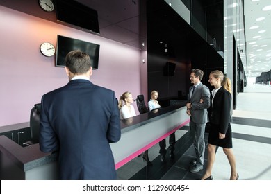 Business People At Reception Or Front Desk In Office Building, Hotel Or Airport