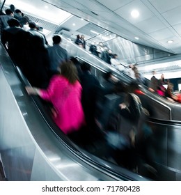 Business People Rushing On The Escalator In Motion Blur On The Subway Station.