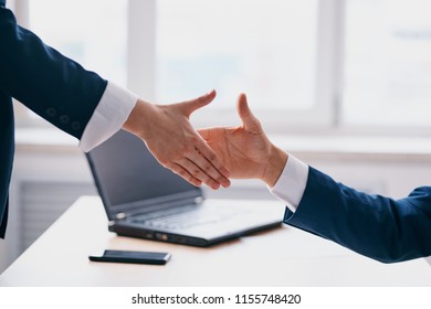 Business people shake hands, laptop in the background                            - Shutterstock ID 1155748420