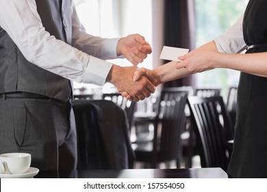 Business people shaking hands after meeting and changing cards in restaurant - Powered by Shutterstock