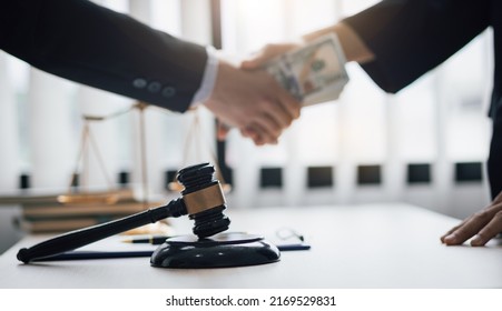 Business people shaking hands and bribe to an attorney to help a lawyer win a court case. The concept of bribing lawyers and paying lawsuits. - Shutterstock ID 2169529831