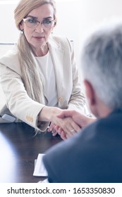 Business people shaking hands at meeting table focus at mature woman - Shutterstock ID 1653350830
