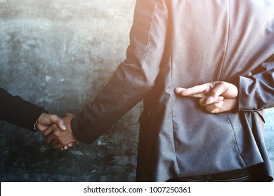 Business people shaking hands and one of them holding fingers crossed behind back, Represents the betrayal.