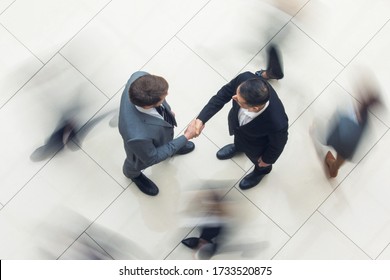 Business People Shaking Hands Standing In A Crowd Of Walking People, Top View