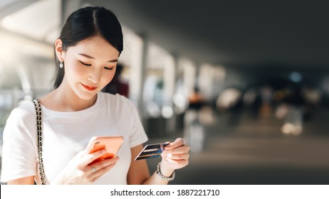 Business people shopping via online application media concept. Happy smile young adult asian woman consumer using creadit card and smartphone. City on day background with copy space. - Shutterstock ID 1887221710
