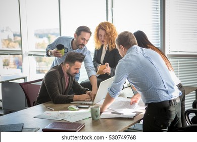 Business people showing team work while working in board room in office interior. People helping one of their colleague to finish new business plan. Business concept. Team work.