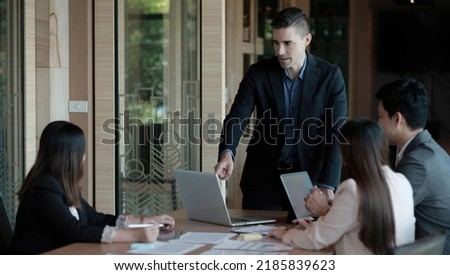 Business people showing team work while working in board room in office interior. People helping one of their colleague to finish new business plan. Business concept. Team work.

