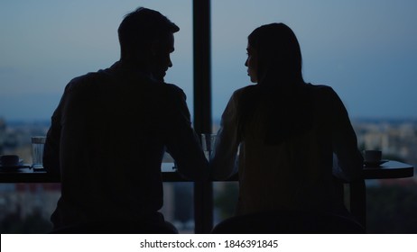 Business people silhouettes talking at workplace in dusk office. Back view of young couple flirting in office on evening city background. Love couple at dating in front of panoramic windows - Shutterstock ID 1846391845