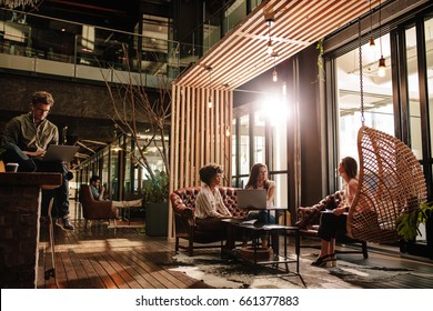 Business people sitting in social room in modern office. Young men and women taking a break from work. - Shutterstock ID 661377883
