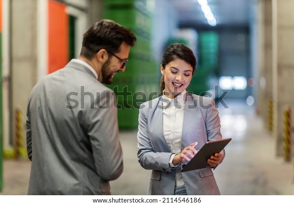 Business people in a small business. A man and a\
woman dressed in a suit stand in the warehouse and check the state\
of stocks in the tablet. A woman with a tablet in her hand shows\
the man the data