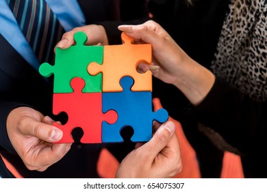 Business people solving jigsaw puzzle. Team holding colorful puzzle pieces in hands