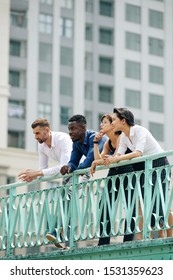 Business people spending time together outdoors, standing on bridge and leaning on handrailing