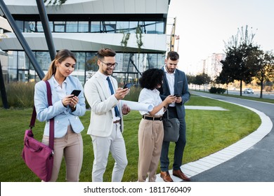 Business People Standing Outside Of Office Buildings Looking At Their Phones.