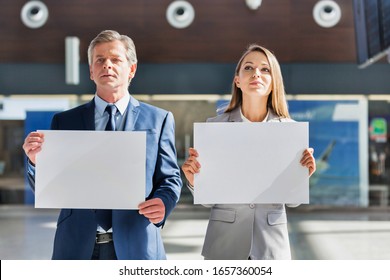 Business People Standing While Holding Blank White Placard In Arrival Area At Airport