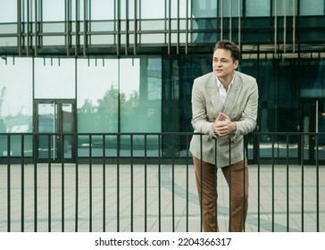 Business, people and success concept: Handsome man in fashinable outfit walking near modern office, summer time