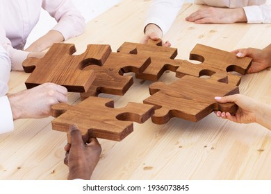 Business People Team Sitting Around Meeting Table And Assembling Wooden Jigsaw Puzzle Pieces Unity Cooperation Ideas Concept