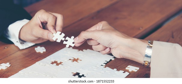 Business People Team Work Holding Two Jigsaw Connecting Couple Puzzle Piece For Matching To Goals Target, Success And Start Up New Project In Office. Business Concept. Close Up Hands. 
