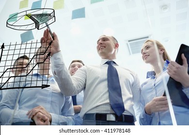 business, people, teamwork and planning concept - smiling business team with marker drawing pie chart on noticeboard in office